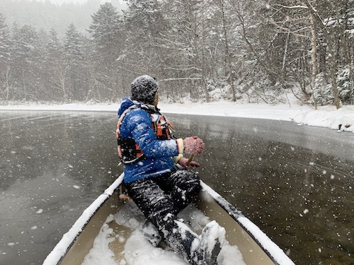 雪が降っている然別湖でカヌーを漕いでいる様子を写した写真