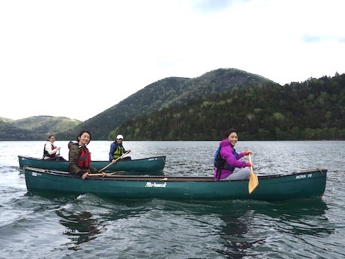 唇山をバックに浮かんでいるカヌーに乗った女性グループの様子を写したツアー写真