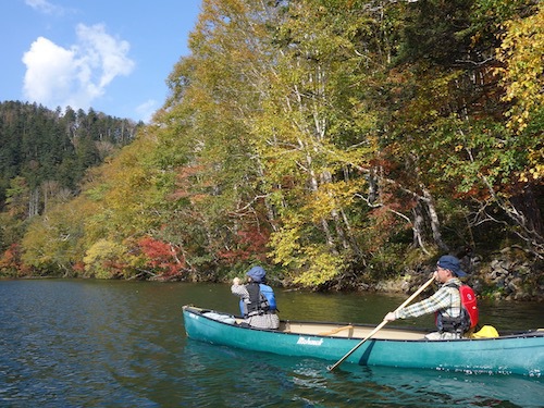 紅葉の始まった然別湖でカヌーに乗っている様子を写したツアー写真
