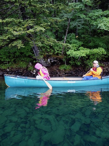 透明度の高い湖面に浮かぶカヌーを写したツアー写真