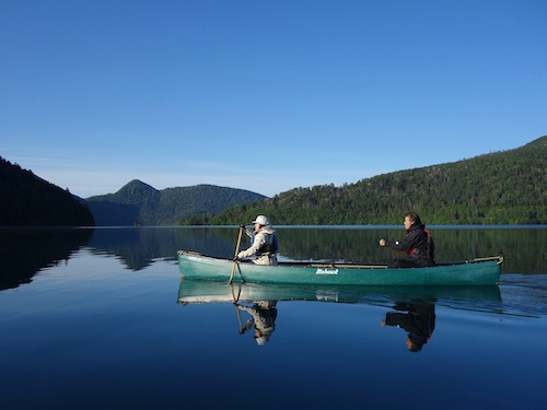 鏡のようになった然別湖の上を進むカヌーを写したツアー写真
